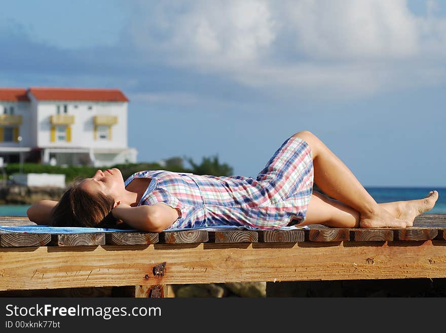 The girl laying down on a promenade in the morning on Sandyport beach in Nassau, The Bahamas. The girl laying down on a promenade in the morning on Sandyport beach in Nassau, The Bahamas.