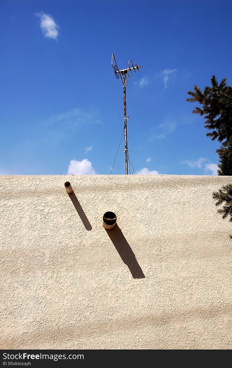 Home television antenna on a roof against  blue sky.