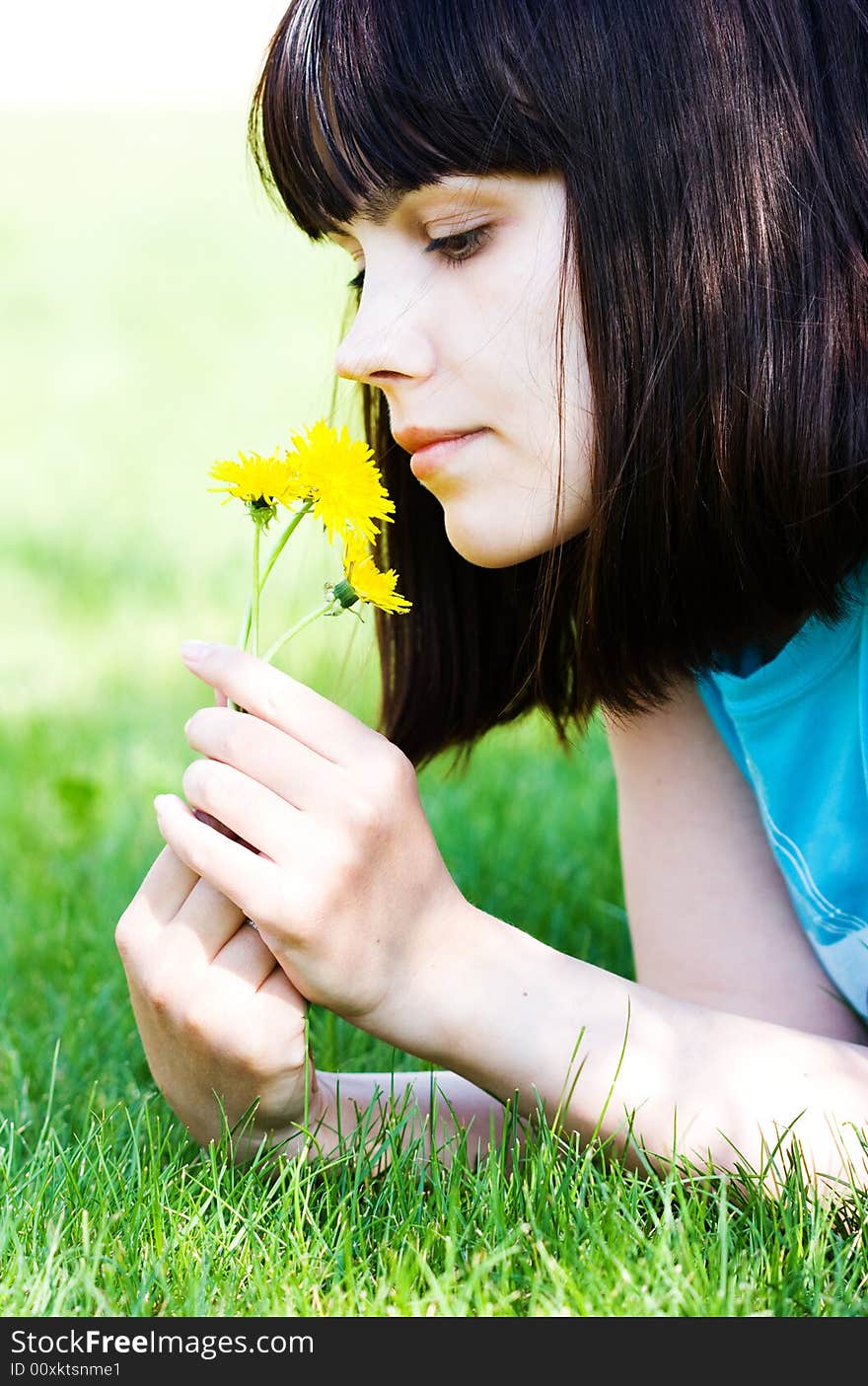 Girl with dandelions lying on the green lawn