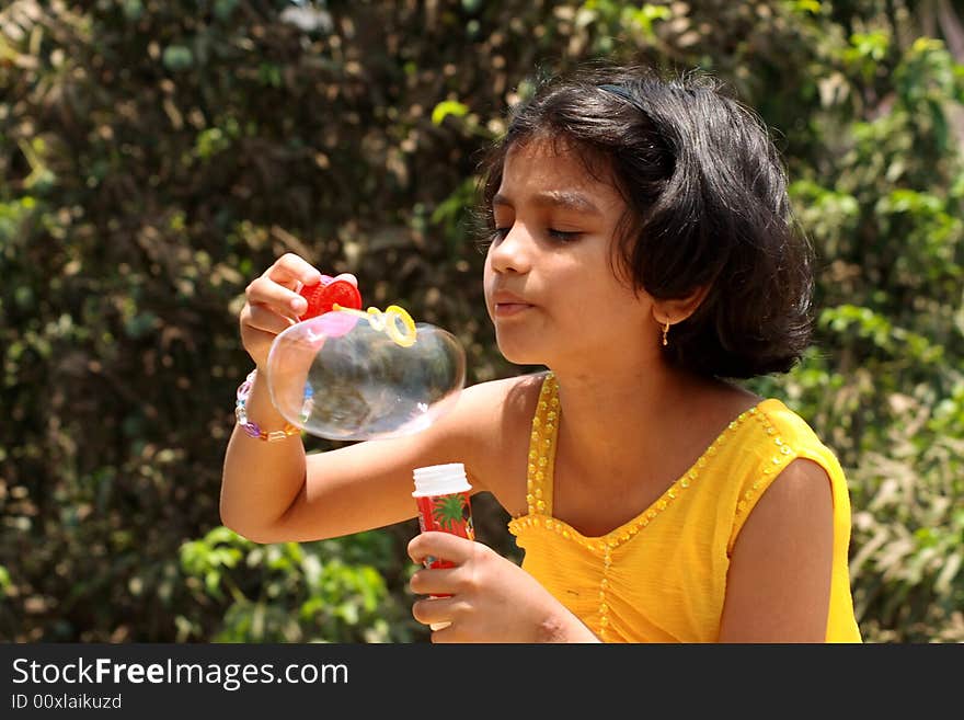 A girl making her hard efforts to blow the bubble. A girl making her hard efforts to blow the bubble.