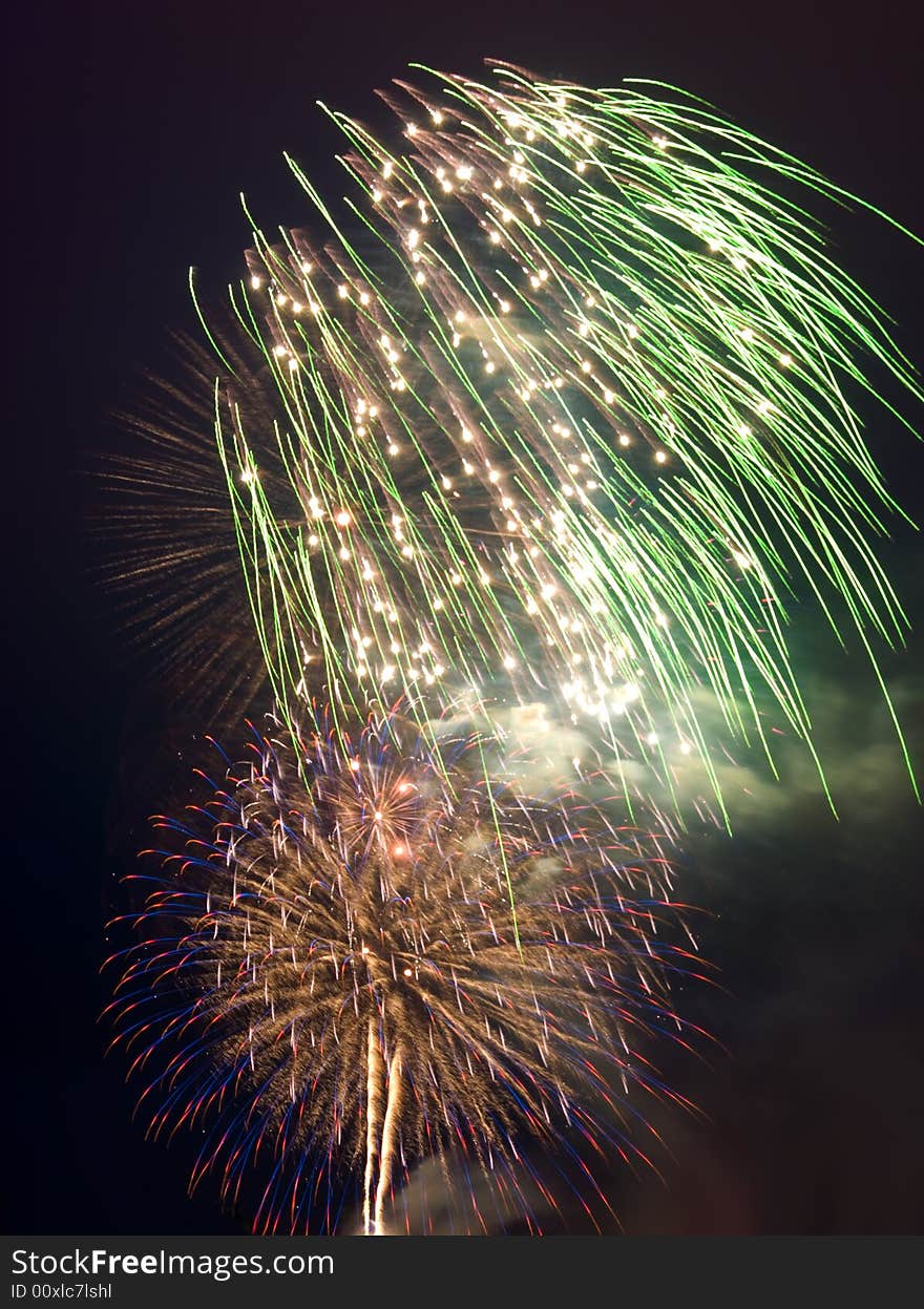 Multiple colourful fireworks explosions on black night sky.