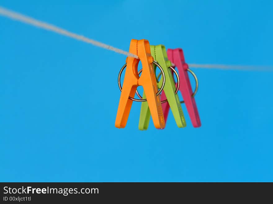 Three washing pegs hanging on a washing line.