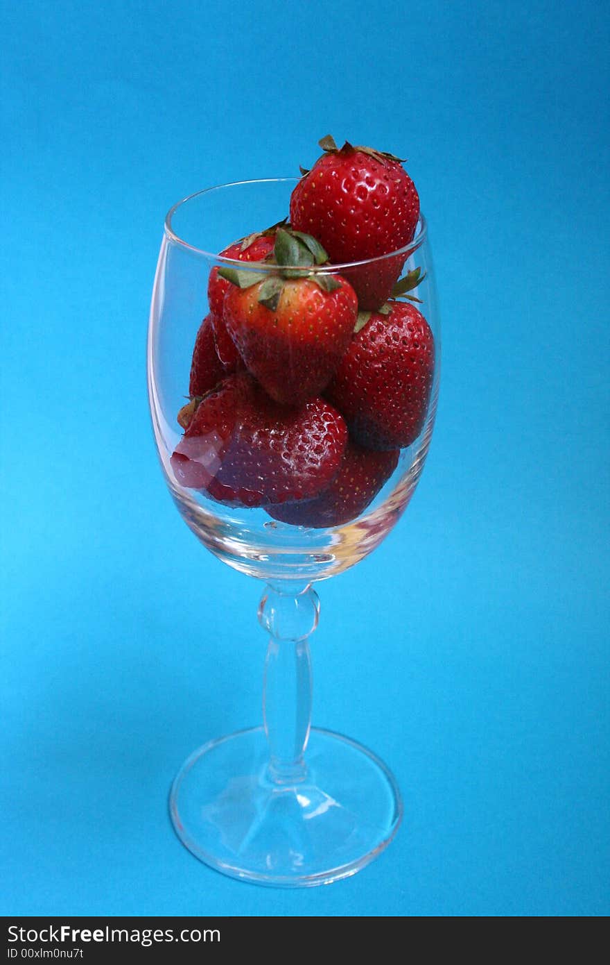 Strawberries in crystal glass with blue background. Strawberries in crystal glass with blue background