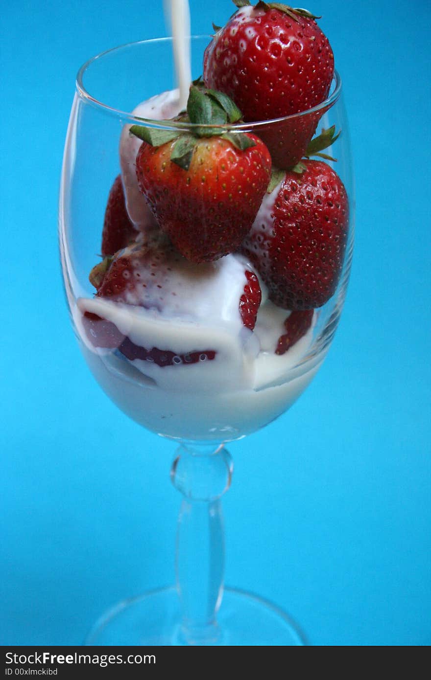 Preparing Strawberry milkshake in crystal glass with blue background