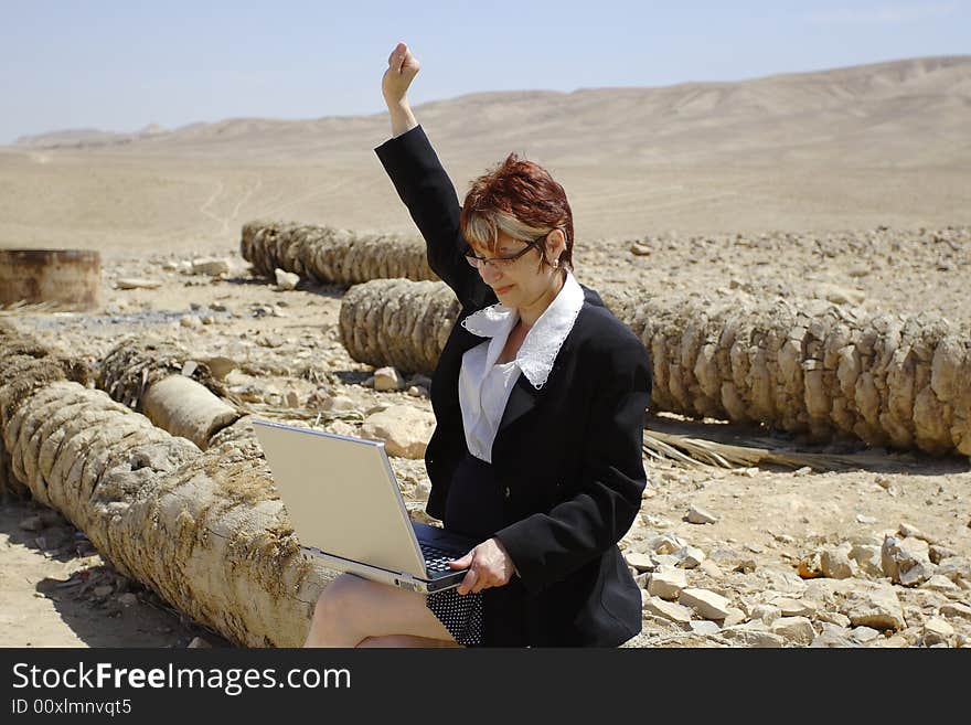 Young woman working with laptop in Judean desert. The successful transaction. Young woman working with laptop in Judean desert. The successful transaction.