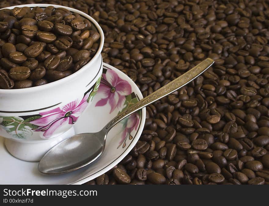 The cup of coffee surrounded by coffee beans