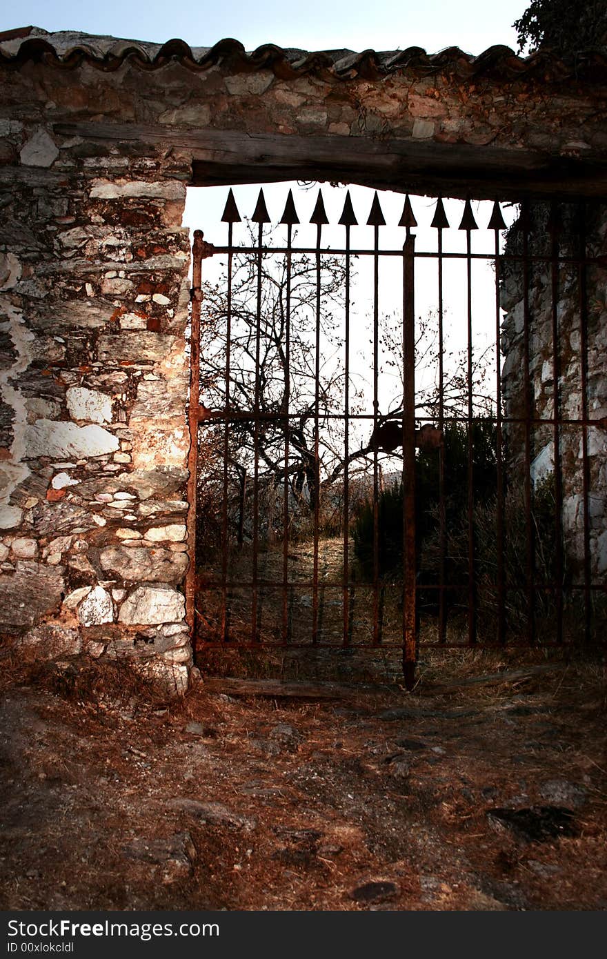 An old gate closing an abandoned cemetery surrounded by a stone wall. An old gate closing an abandoned cemetery surrounded by a stone wall