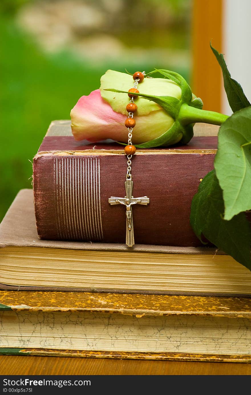 Religious still life with small cross, old book and rose