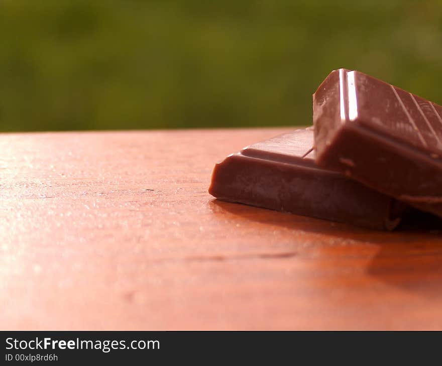 Two brick of chocolate on wooden bench.