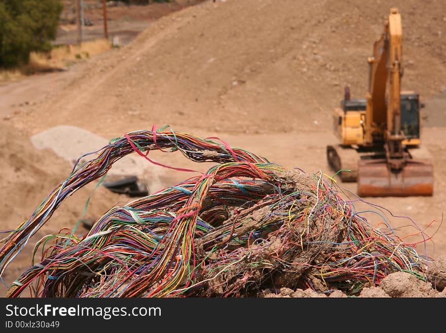 Closeup of a colorful bundle of old telephone wires that had been dug up by a trackhoe which is in the background. Closeup of a colorful bundle of old telephone wires that had been dug up by a trackhoe which is in the background.