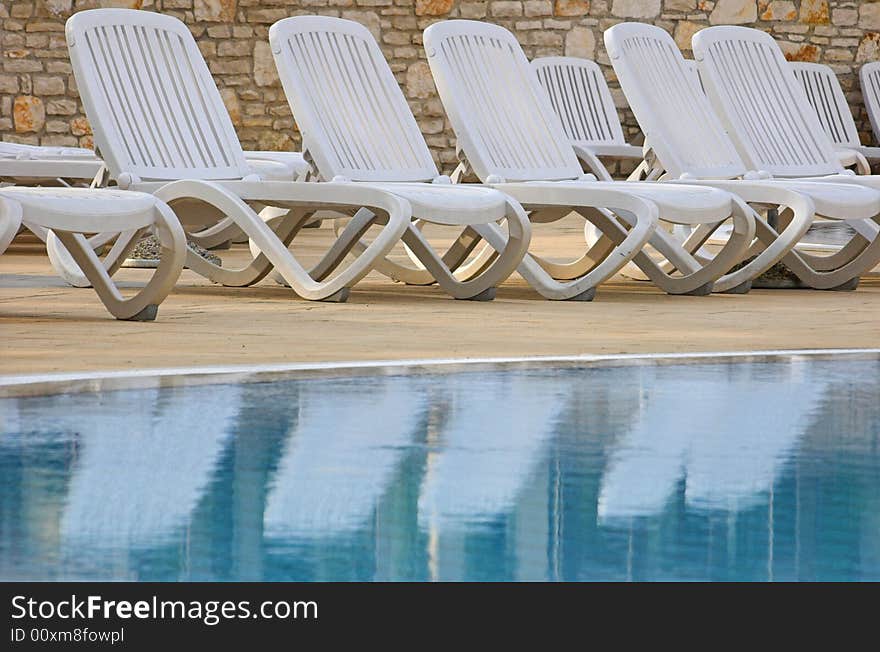 Plastic white chairs standing on a swimming pool terrace