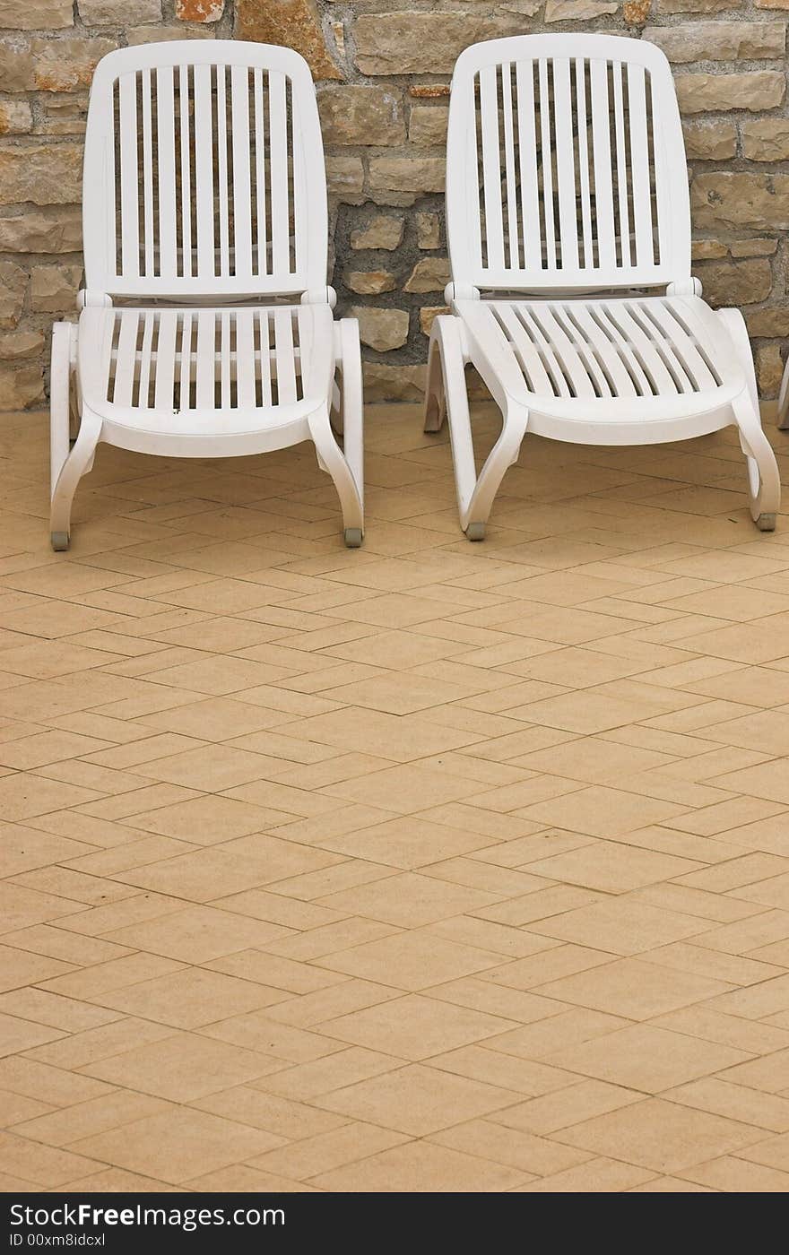 Plastic white chairs standing on a swimming pool terrace