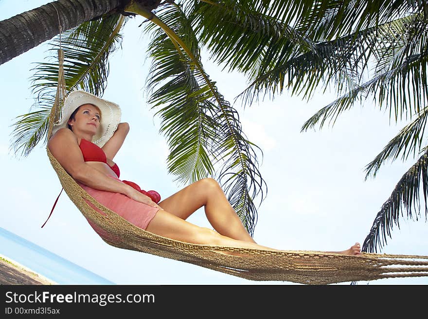 View of nice woman lounging in hammock in tropical environment