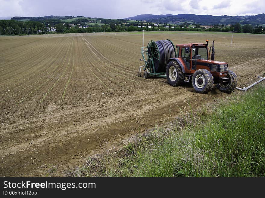 A tractor on a farm with haybales behind.