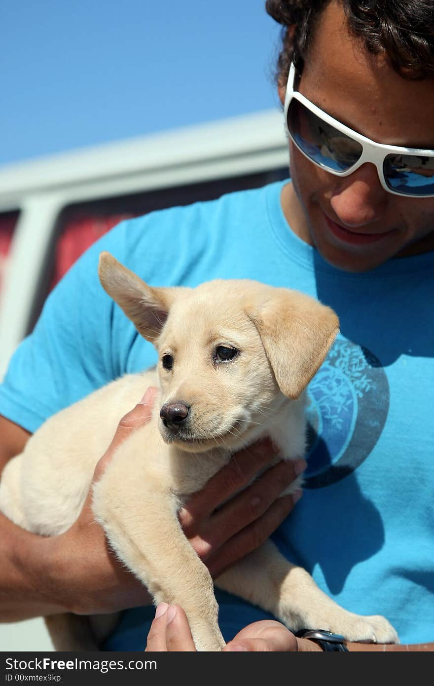 Young man holding his labrador puppy. Young man holding his labrador puppy