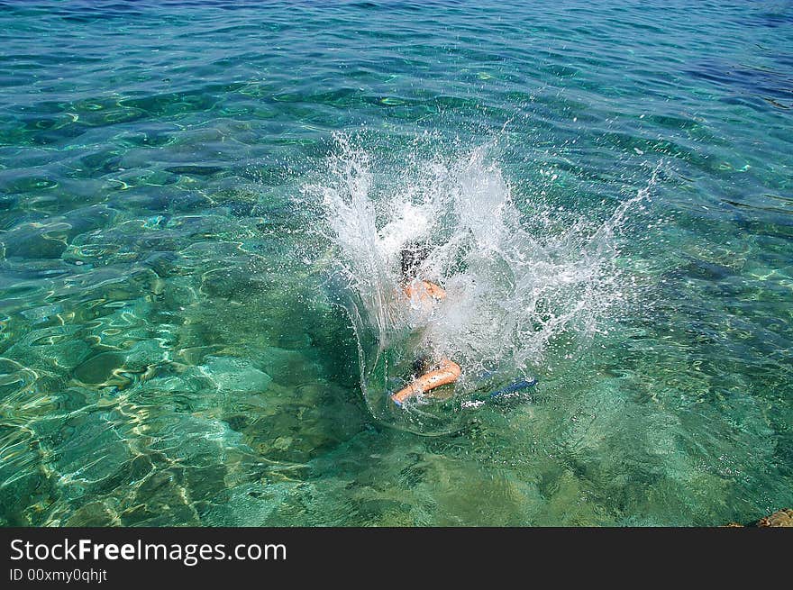 A boy jumping in the limpid sea of Isola d'Elba in Tuscany. A boy jumping in the limpid sea of Isola d'Elba in Tuscany