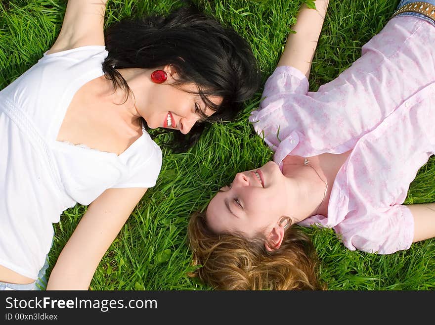 Smiling women rest on the green grass