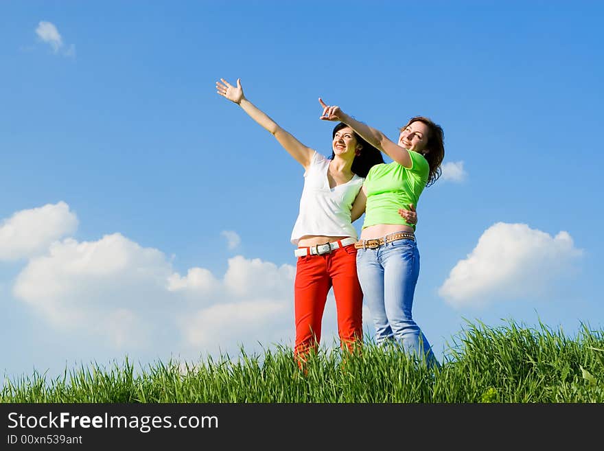 Two young women on a green meadow and show something