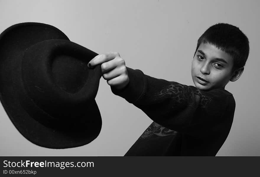 Young boy holding out a black hat. Young boy holding out a black hat