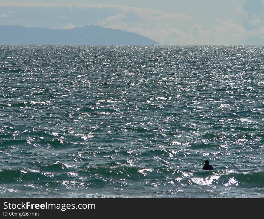 A lone swimmer off the coast of Newport Beach California contemplates Santa Catalina Island