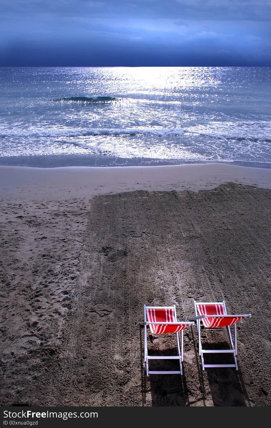 Red chairs contrast with the strength of the sunlight on the sea. Red chairs contrast with the strength of the sunlight on the sea