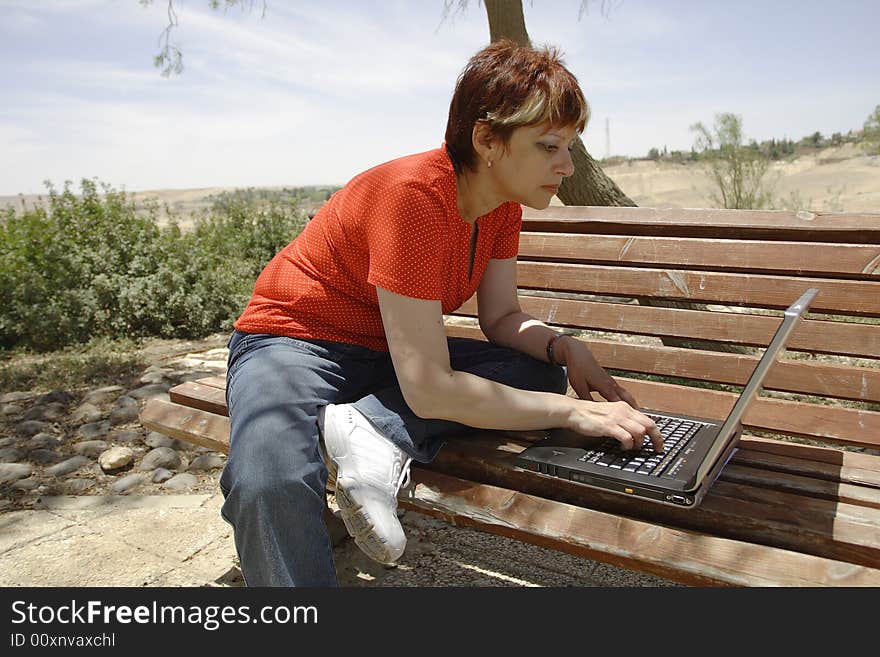 A young woman using a portable computer outside. A young woman using a portable computer outside