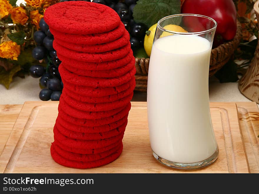 Stack of red sugar cookies and glass of milk in kitchen. Stack of red sugar cookies and glass of milk in kitchen.