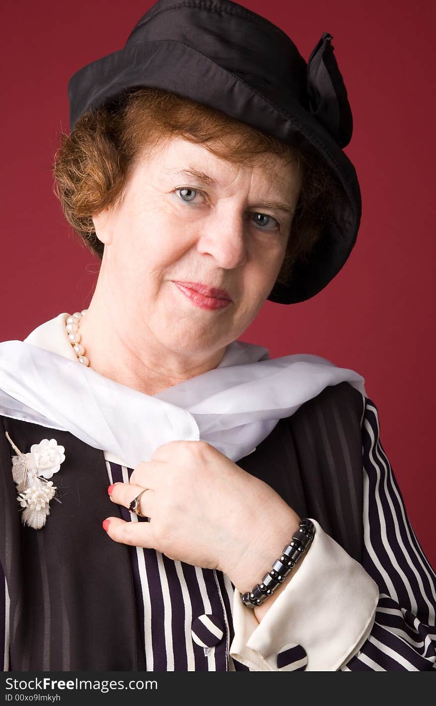 The elderly woman in a hat on a red background. The elderly woman in a hat on a red background.