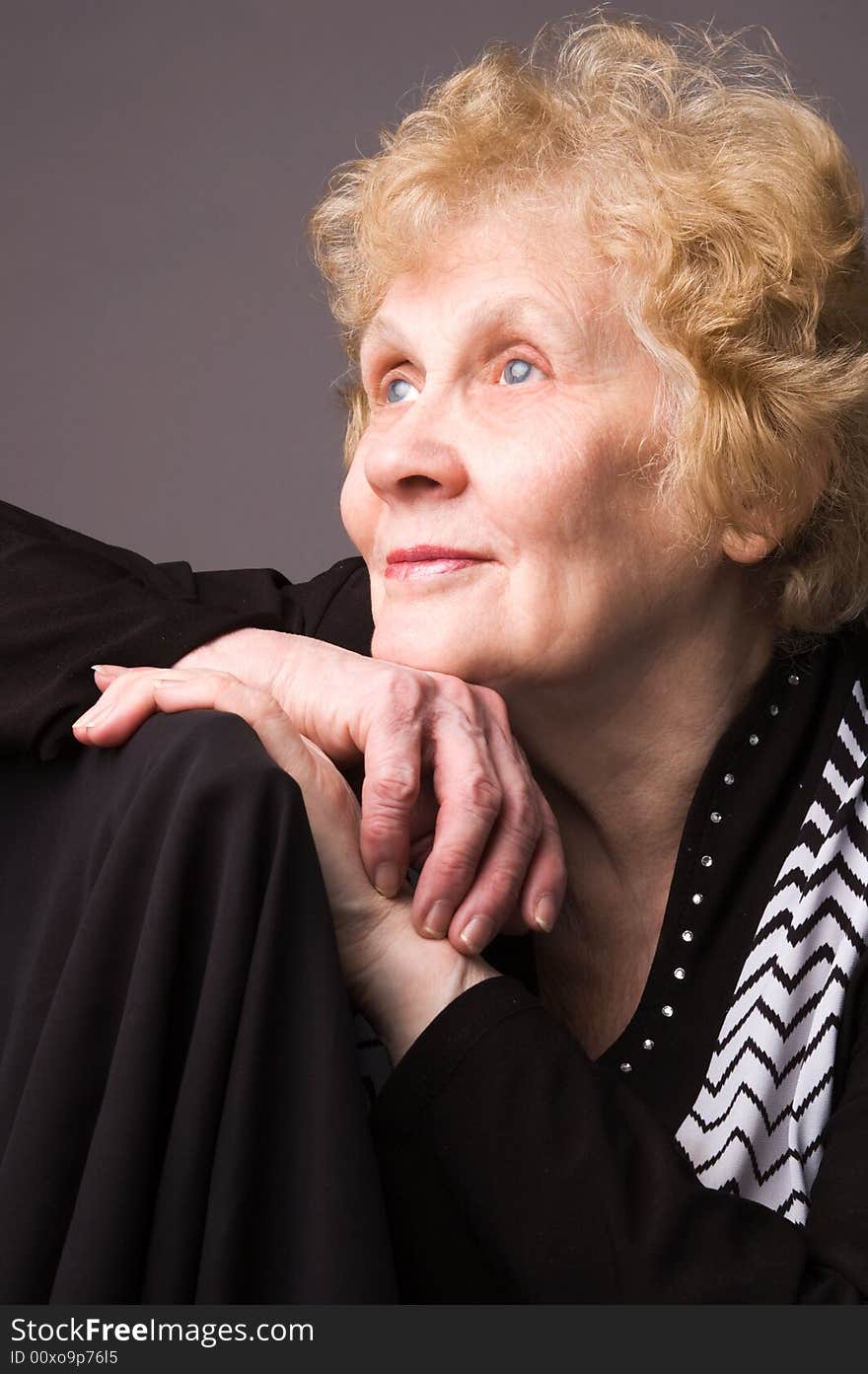 The elderly woman in a black dress on a grey background. The elderly woman in a black dress on a grey background.