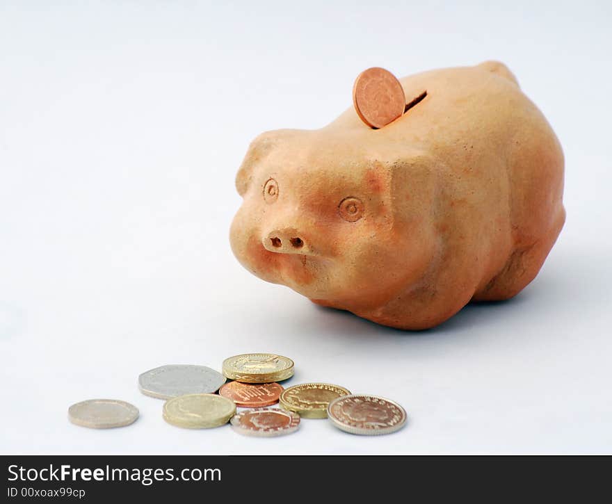 British coins and piggy bank over white. British coins and piggy bank over white