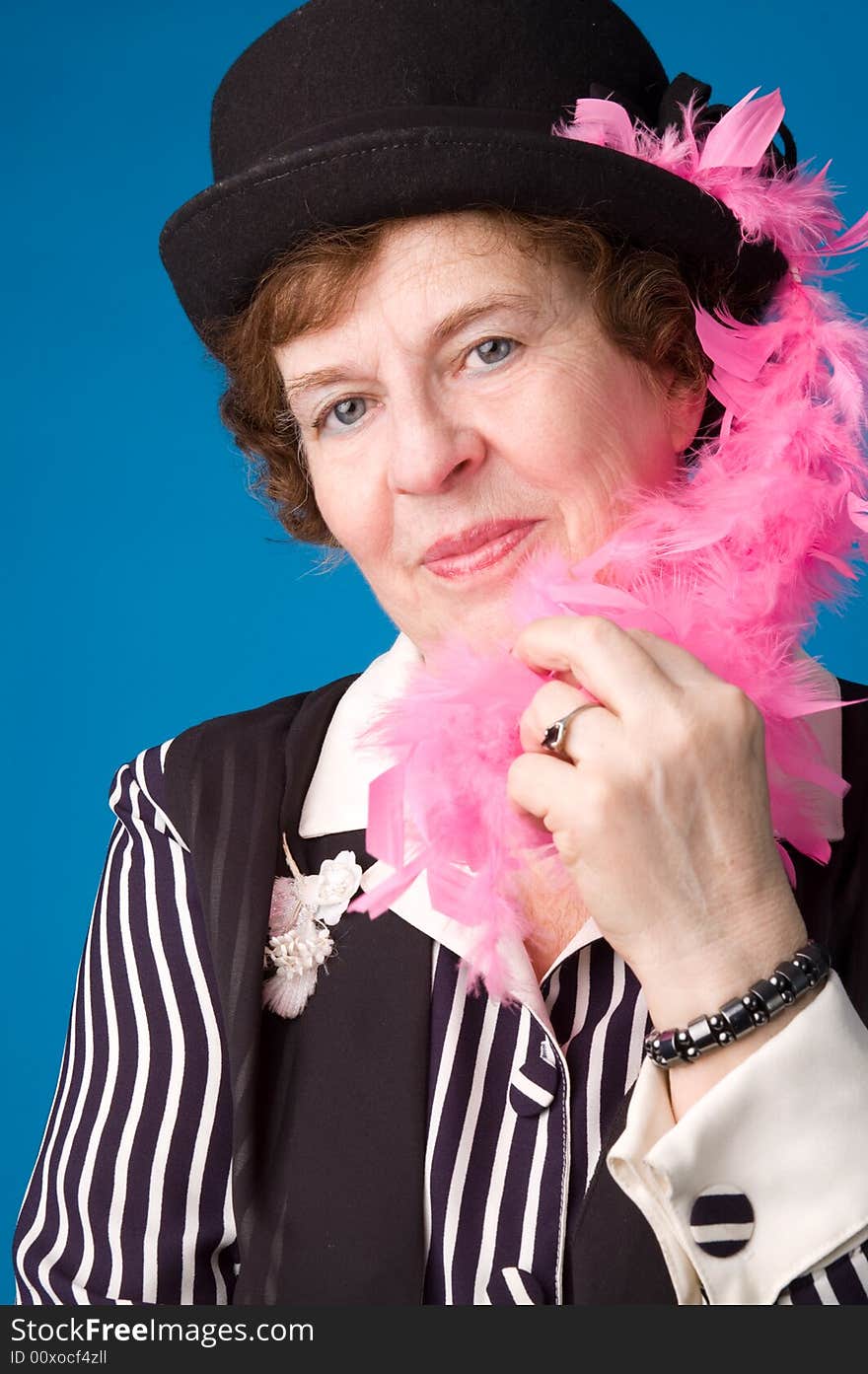 The cheerful elderly woman in black hat on a blue background. The cheerful elderly woman in black hat on a blue background.