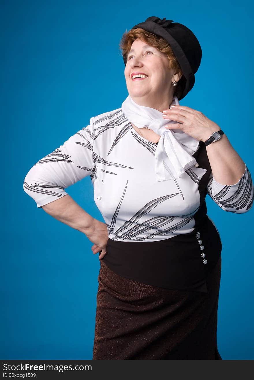 The cheerful elderly woman in a white dress on a blue background. The cheerful elderly woman in a white dress on a blue background.