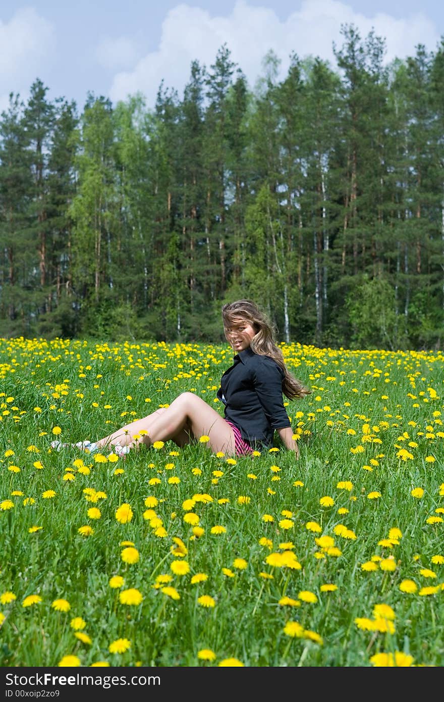 Young girl in short skirt on dandelion field