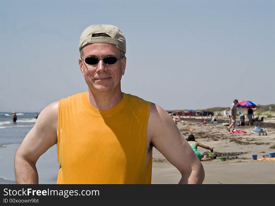 A smiling man at the beach wearing sunglasses and his baseball hat on backwards. A smiling man at the beach wearing sunglasses and his baseball hat on backwards.