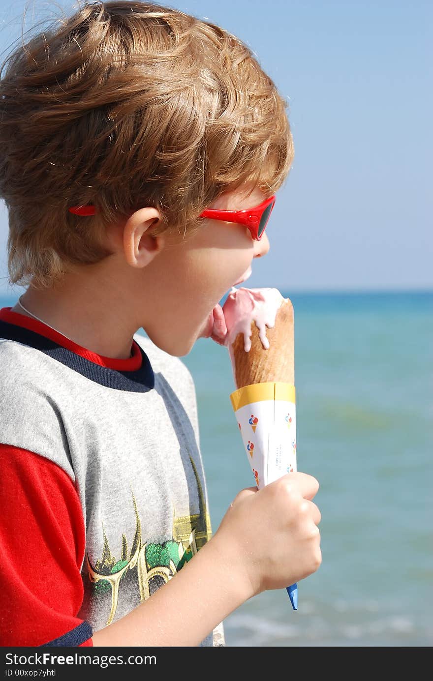 On seacoast the boy eats ice-cream