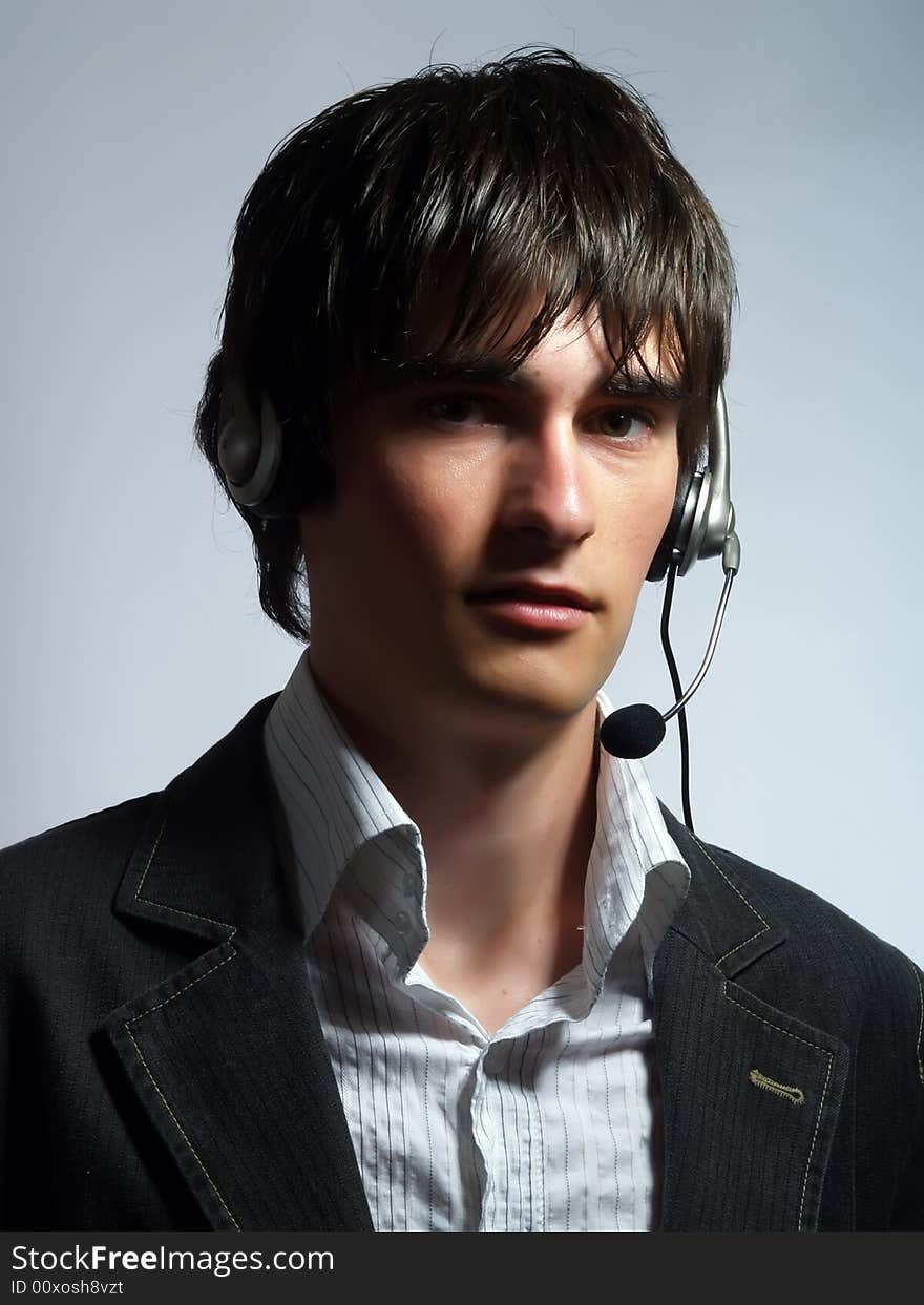 A portrait about an attractive call center operator man who is smiling and he has a headphone. He is wearing a white shirt and a black suit. A portrait about an attractive call center operator man who is smiling and he has a headphone. He is wearing a white shirt and a black suit.