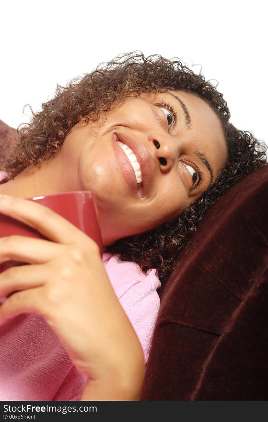 Young woman having her morning cup of coffee on the couch and laughing. Young woman having her morning cup of coffee on the couch and laughing