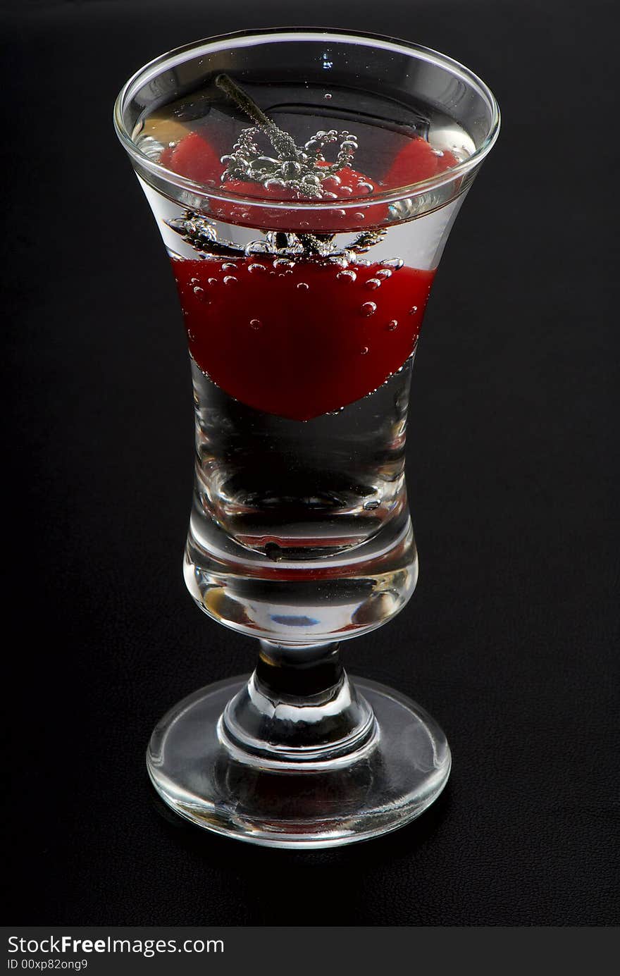 Tomato in a wine-glass. A black background. Studio shooting. Tomato in a wine-glass. A black background. Studio shooting