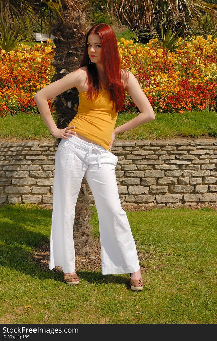 Cute girl  in yellow top and white pants in beautiful gardens. Cute girl  in yellow top and white pants in beautiful gardens