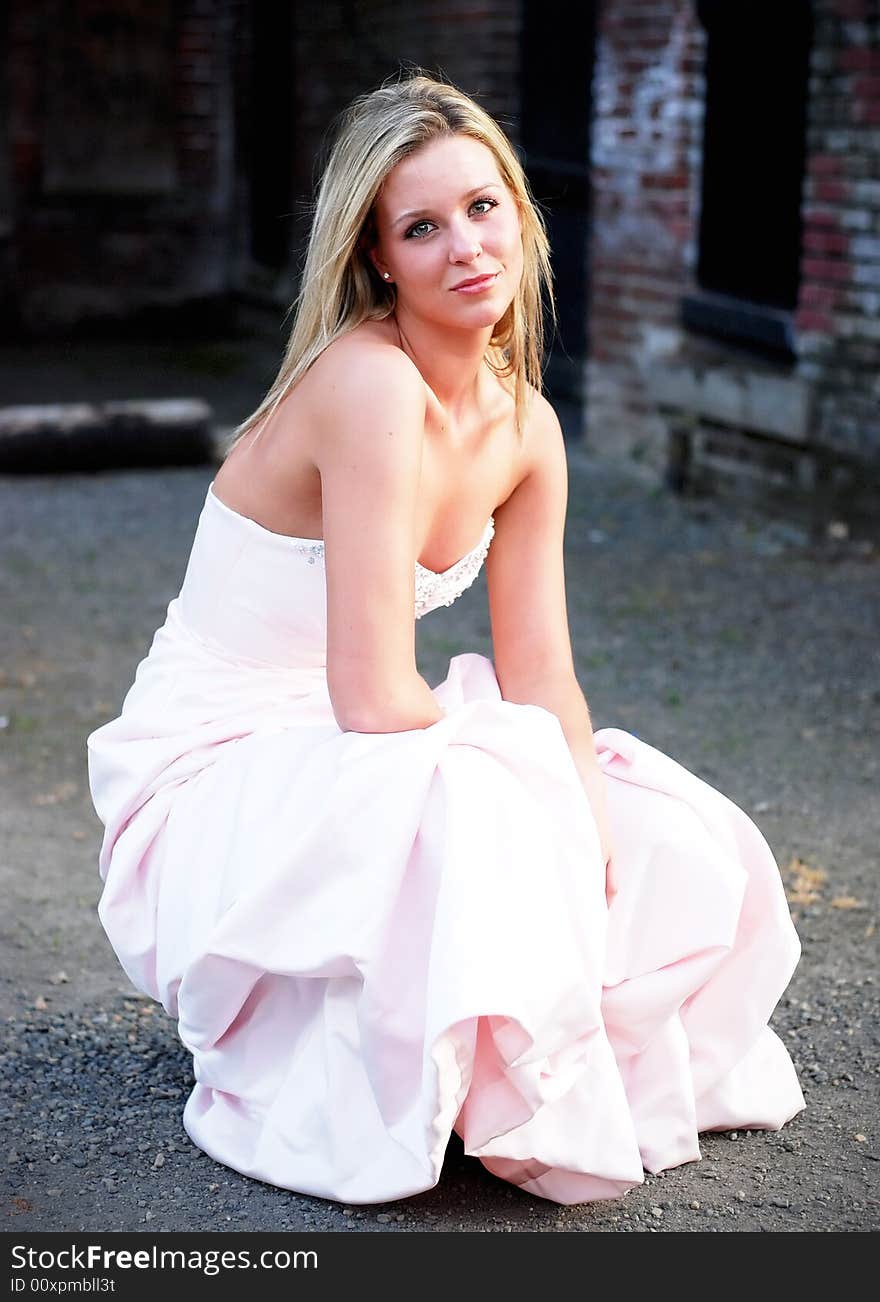 Attractive blond woman kneeling down in a bridesmaid's dress. Vertically framed shot. Attractive blond woman kneeling down in a bridesmaid's dress. Vertically framed shot.