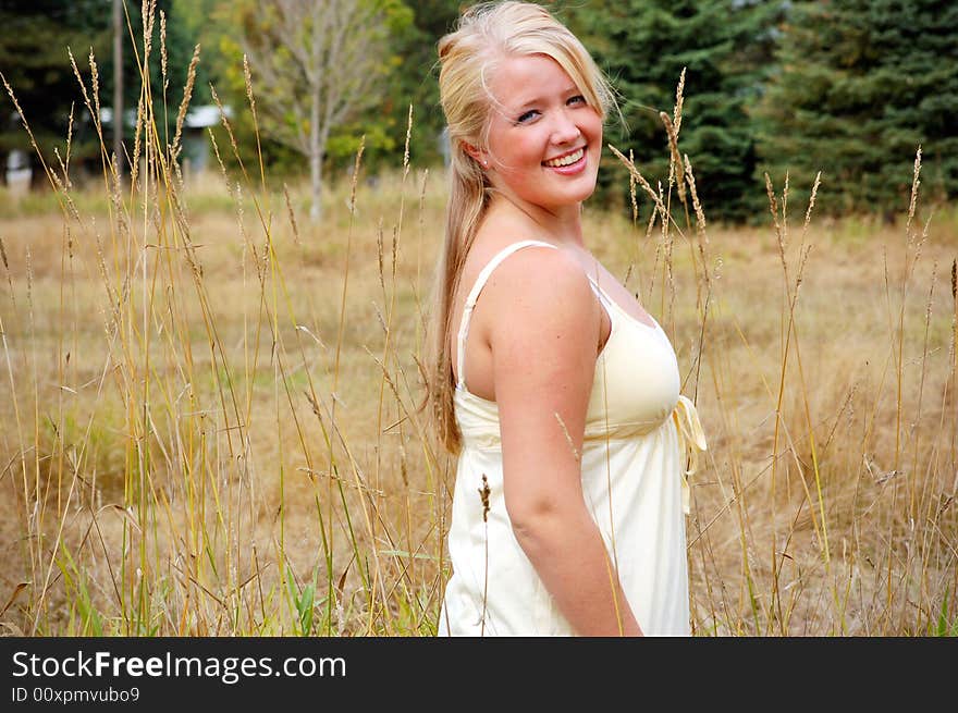 Smiling teenage girl, with blonde hair and blue eyes, standing in a straw colored field. Smiling teenage girl, with blonde hair and blue eyes, standing in a straw colored field.