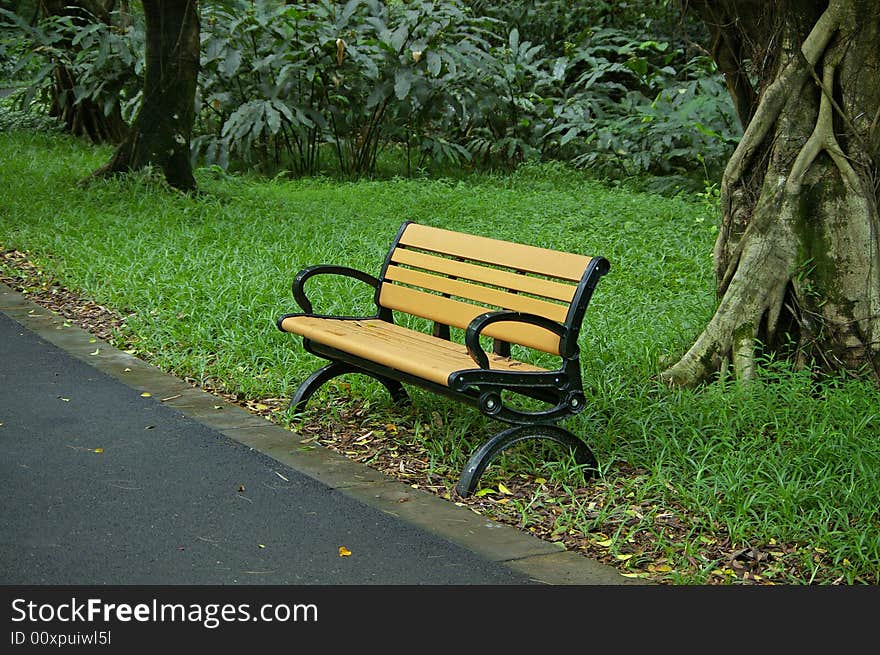 A yellow chair by road side in the park.