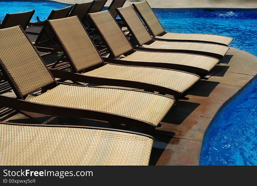 Lounge chairs besides a swimming pool. Lounge chairs besides a swimming pool