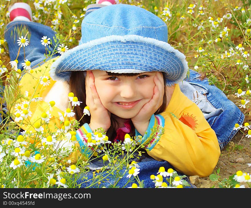 Girl with brown eyes rests on the chamomile field. Little coquette with a hat. Girl with brown eyes rests on the chamomile field. Little coquette with a hat.