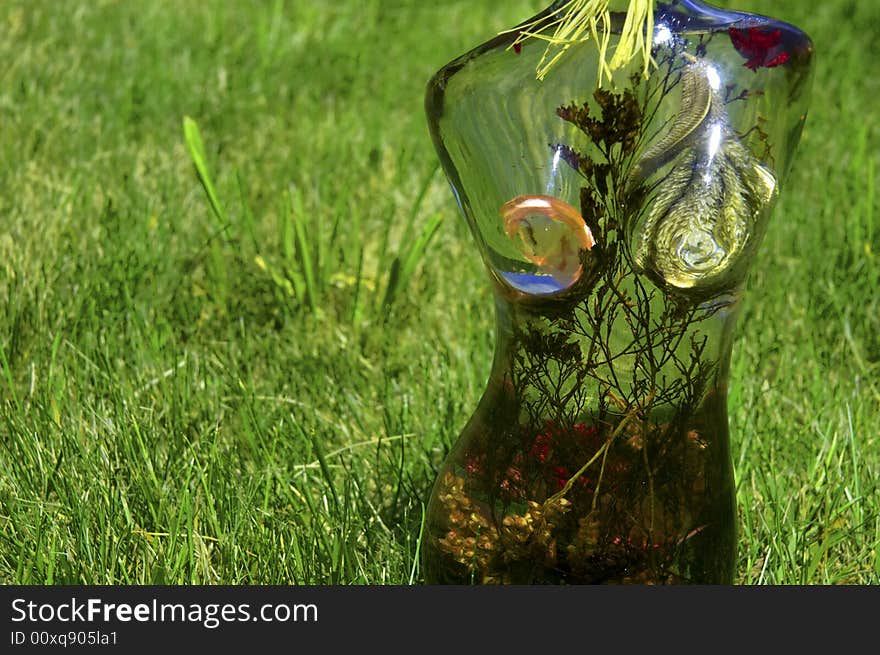 Glass woman with flowers on a background of green grass. Glass woman with flowers on a background of green grass