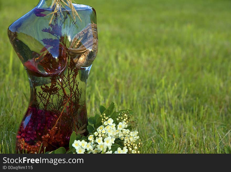 Glass woman with flowers on a background of green grass. Glass woman with flowers on a background of green grass