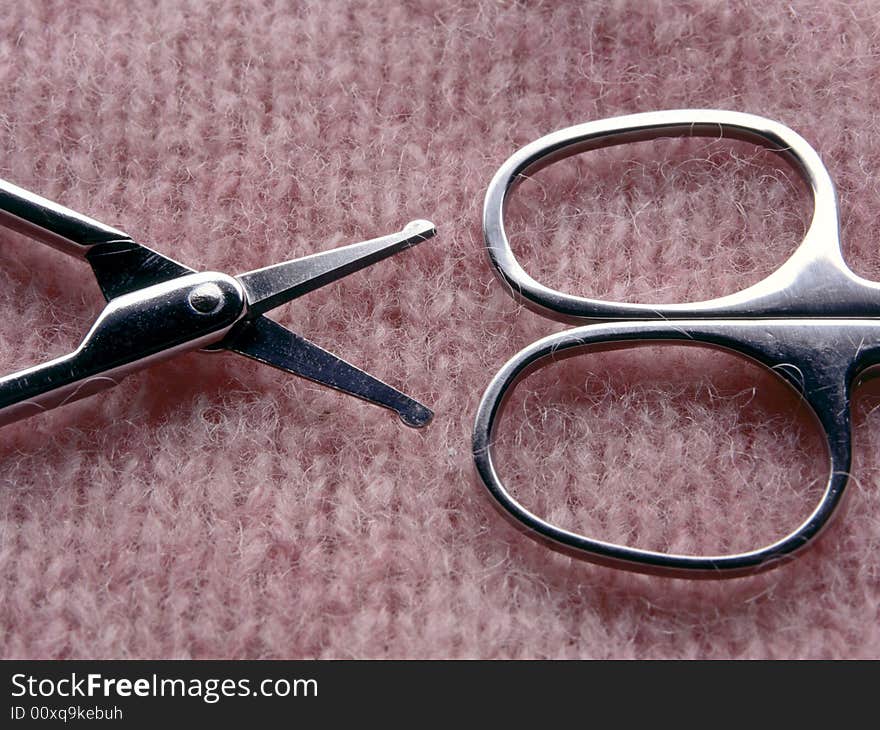 Two pair of scissors on textured pink background.  Half of each pair of scissors are in the image.  The pink background is a soft textile with a knit pattern.