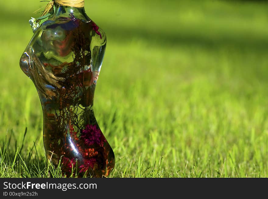 Glass woman with flowers on a background of green lawn. Glass woman with flowers on a background of green lawn