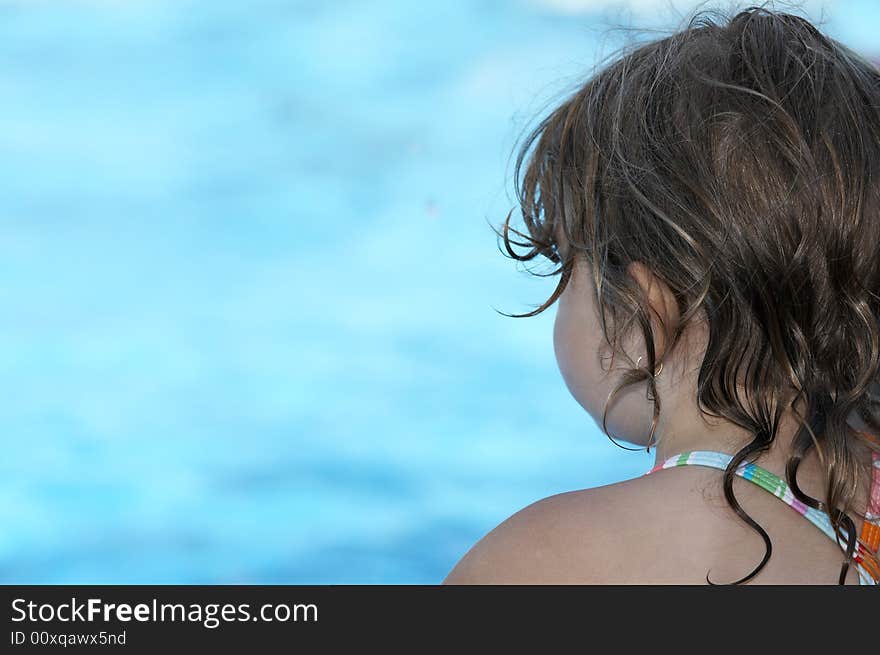 A cute little girl looking at pool water during the summer. A cute little girl looking at pool water during the summer