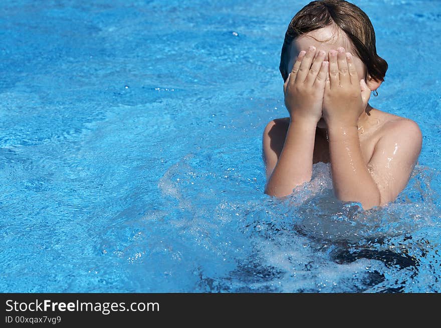 A boy playing in a pool of water during the summer. A boy playing in a pool of water during the summer